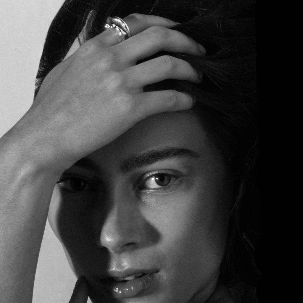 Black and white portrait of model wearing the Recollections silver ring on hand near face